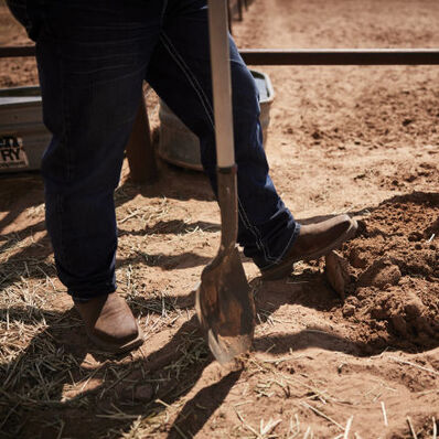 Rancher digging a hole wearing Durango Workin' Rebel Texas flag steel toe boots